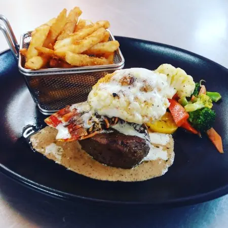 Surf and turf: steak and lobster with vegetables and a basket of fries